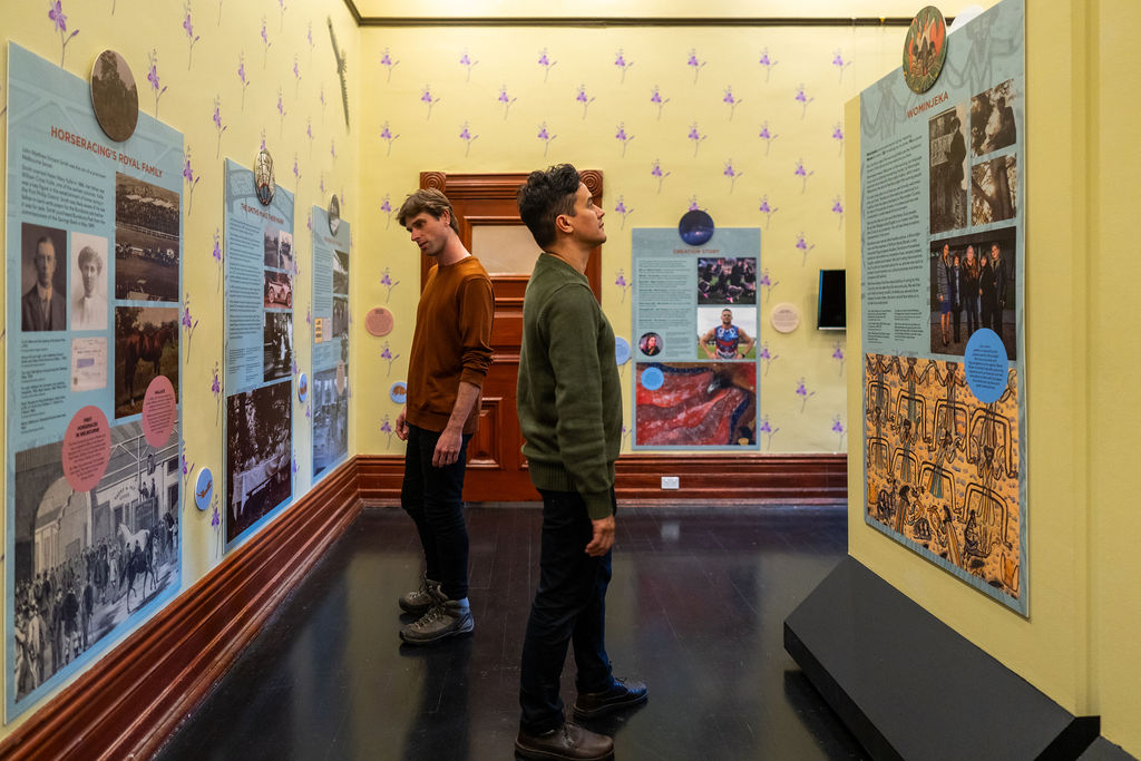 Two people survey the walls of a historical art display