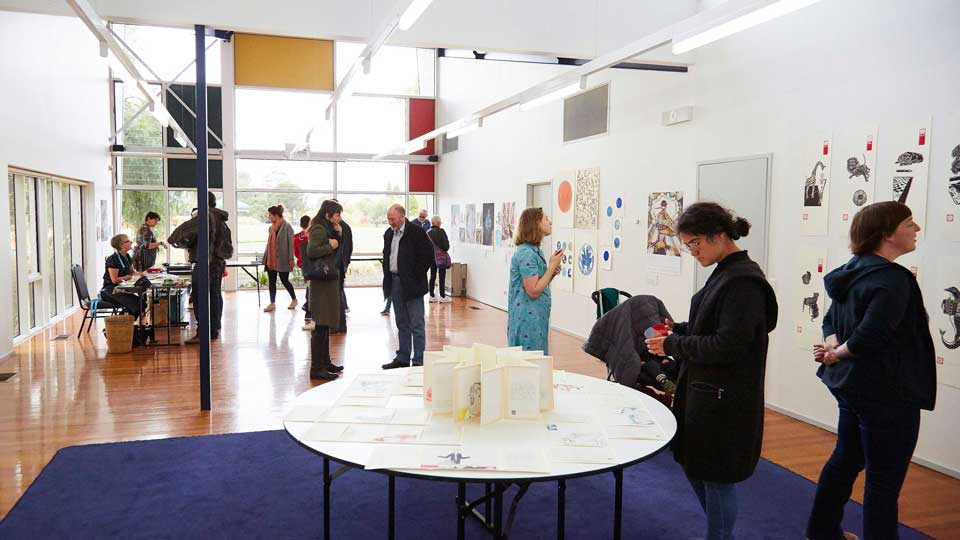 People viewing an exhibition of painting and artwork in the studio at Darebin Arts Centre