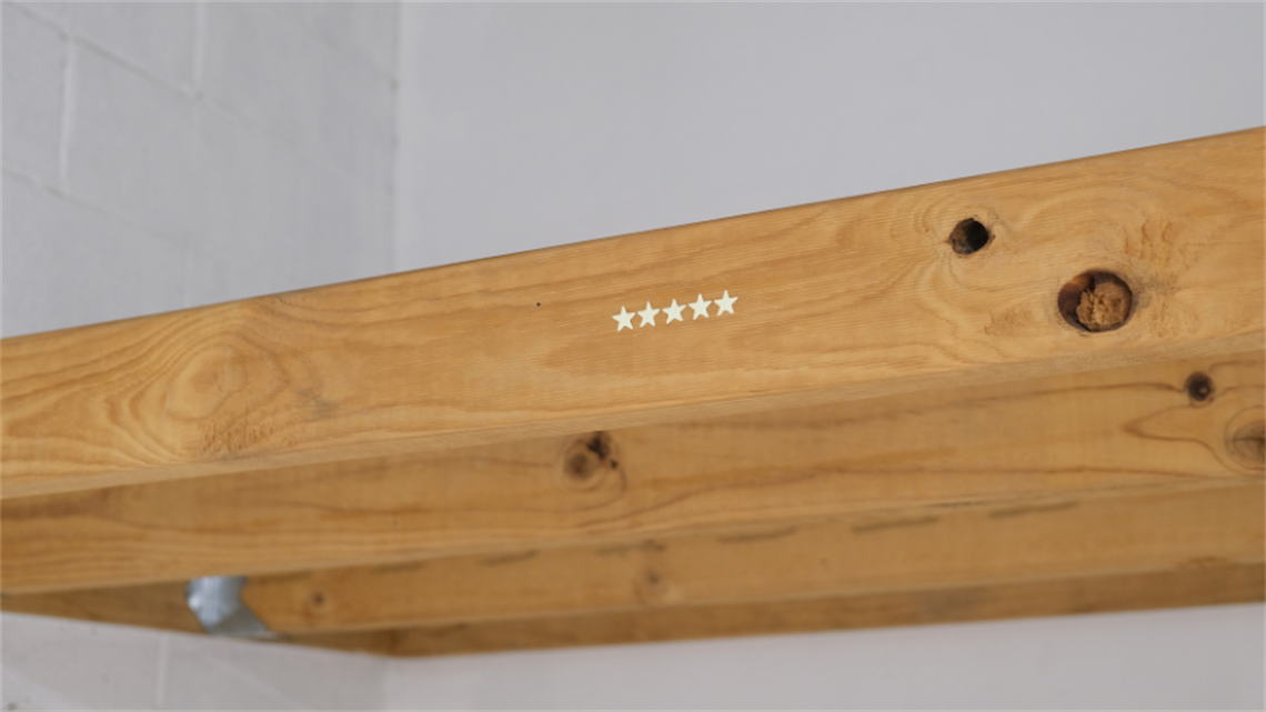 Five gold, plastic glow-in-the-dark stars stuck on a wooden beam