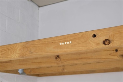 Five gold, plastic glow-in-the-dark stars stuck on a wooden beam 