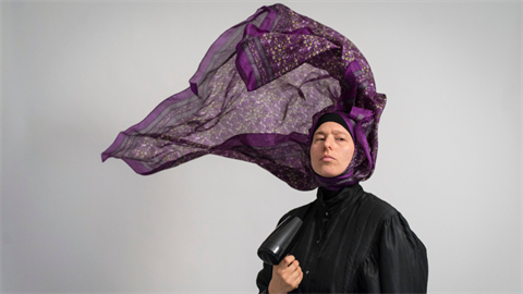 A person with a purple scarf billowing from their head