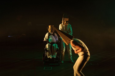 A person wearing a cone-shaped mask bends over with their hands tucked in front of their stomach.