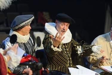 Two men wearing Renaissance costumes chat with one another.