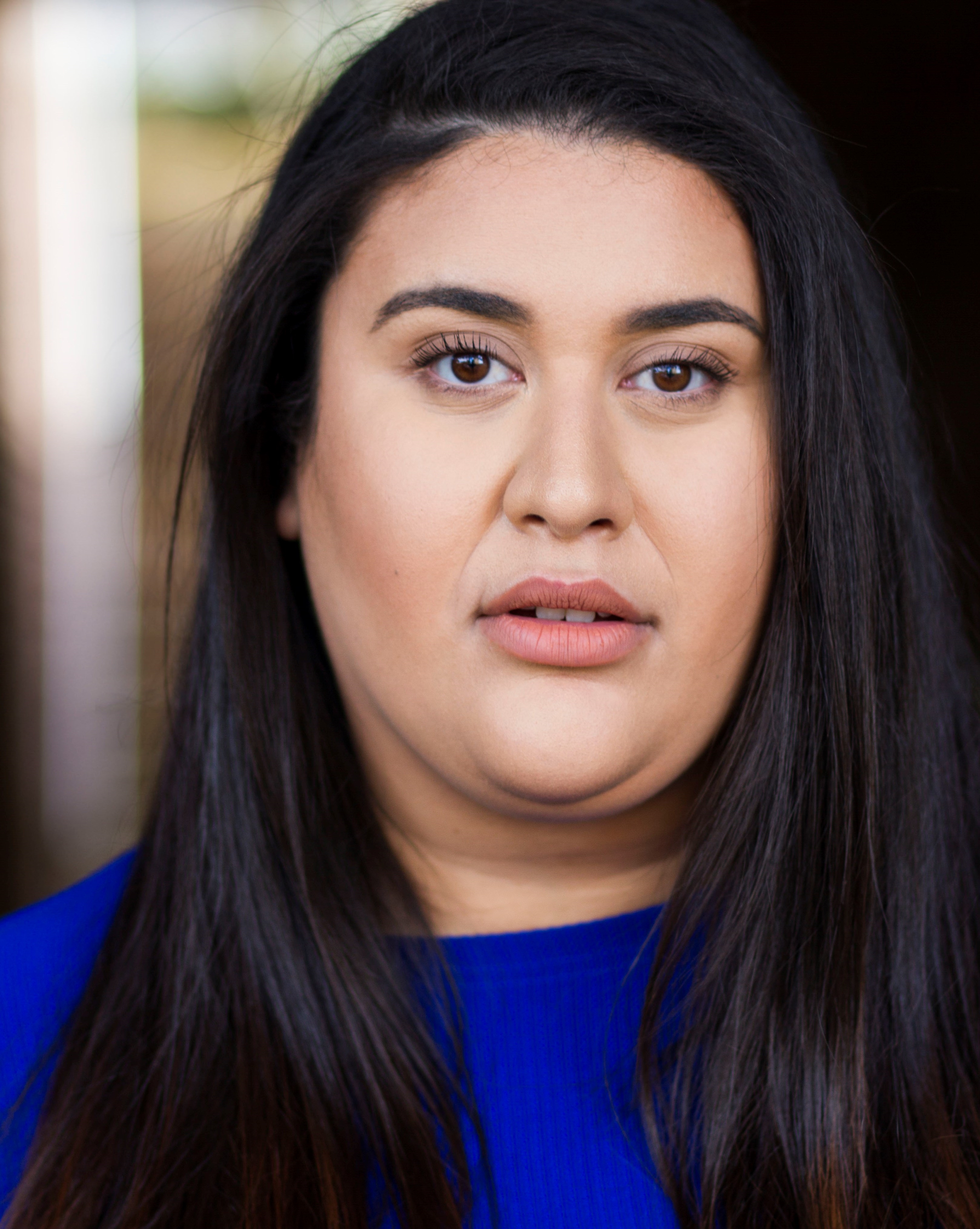 A woman with long dark hair wears a blue top.