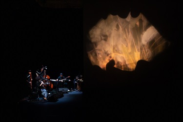 A five-person music group next to a projection screen.