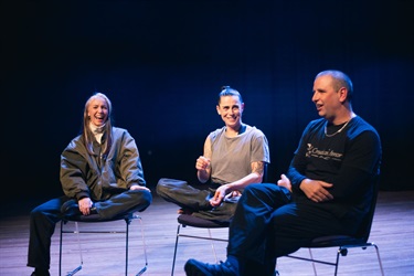 Three people sat in chairs side by side one another.