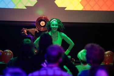 A person wearing a white tank top stands in front of a crowd.