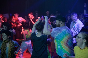 A large crowd dances on a dancefloor.