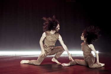 Two people dance on a slick wooden floor.