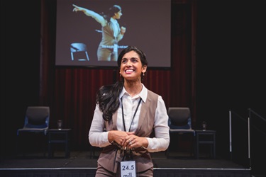 A woman smiles to an audience.