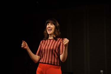 A woman half raises her arms up.