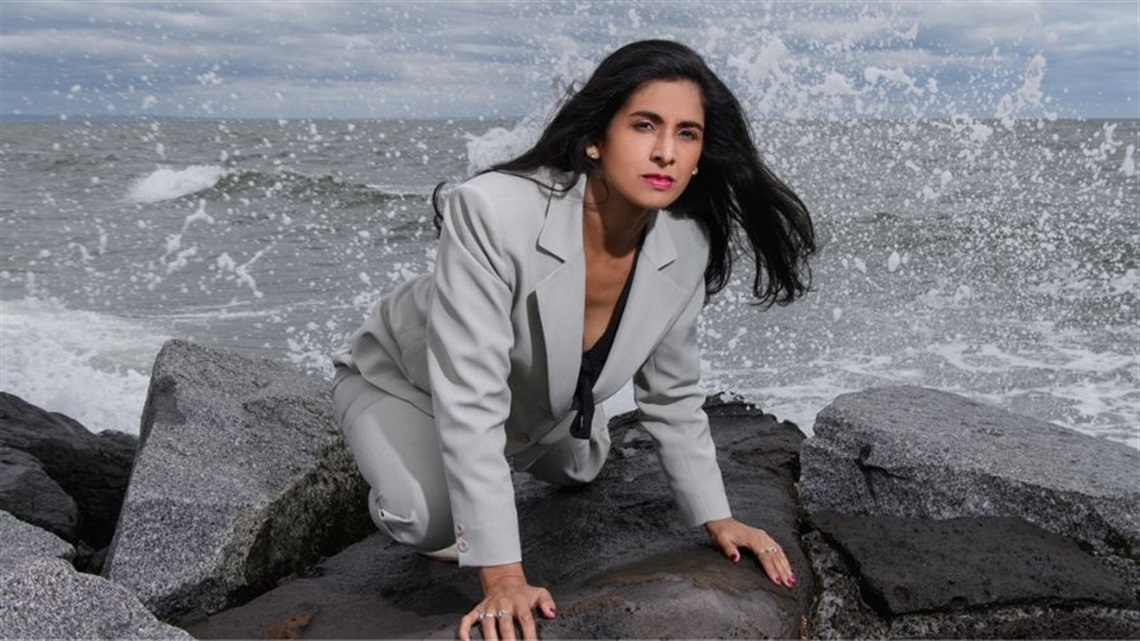 A woman crawling on ocean rocks.