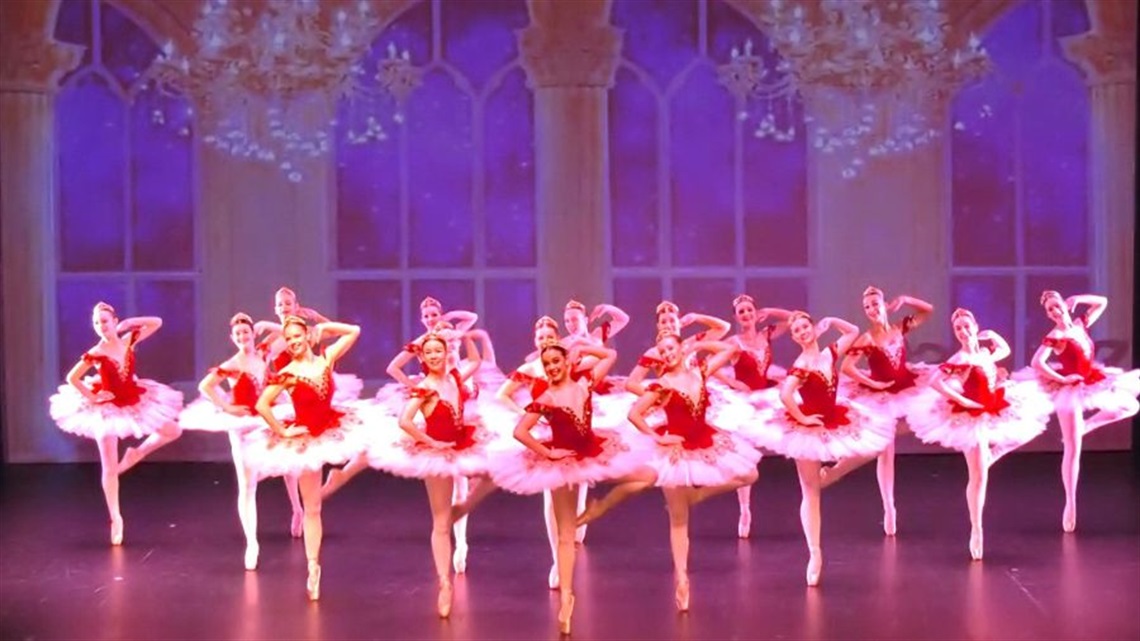 A line of female ballet dancers wearing red and white tutus.