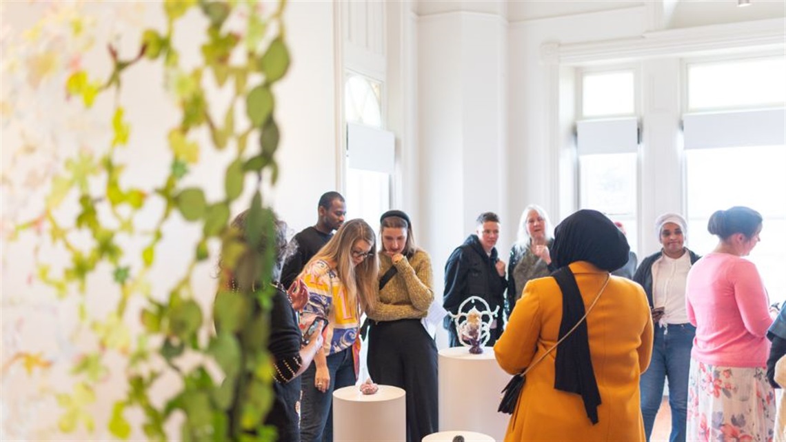 A group of people walk around an art sculpture exhibition.