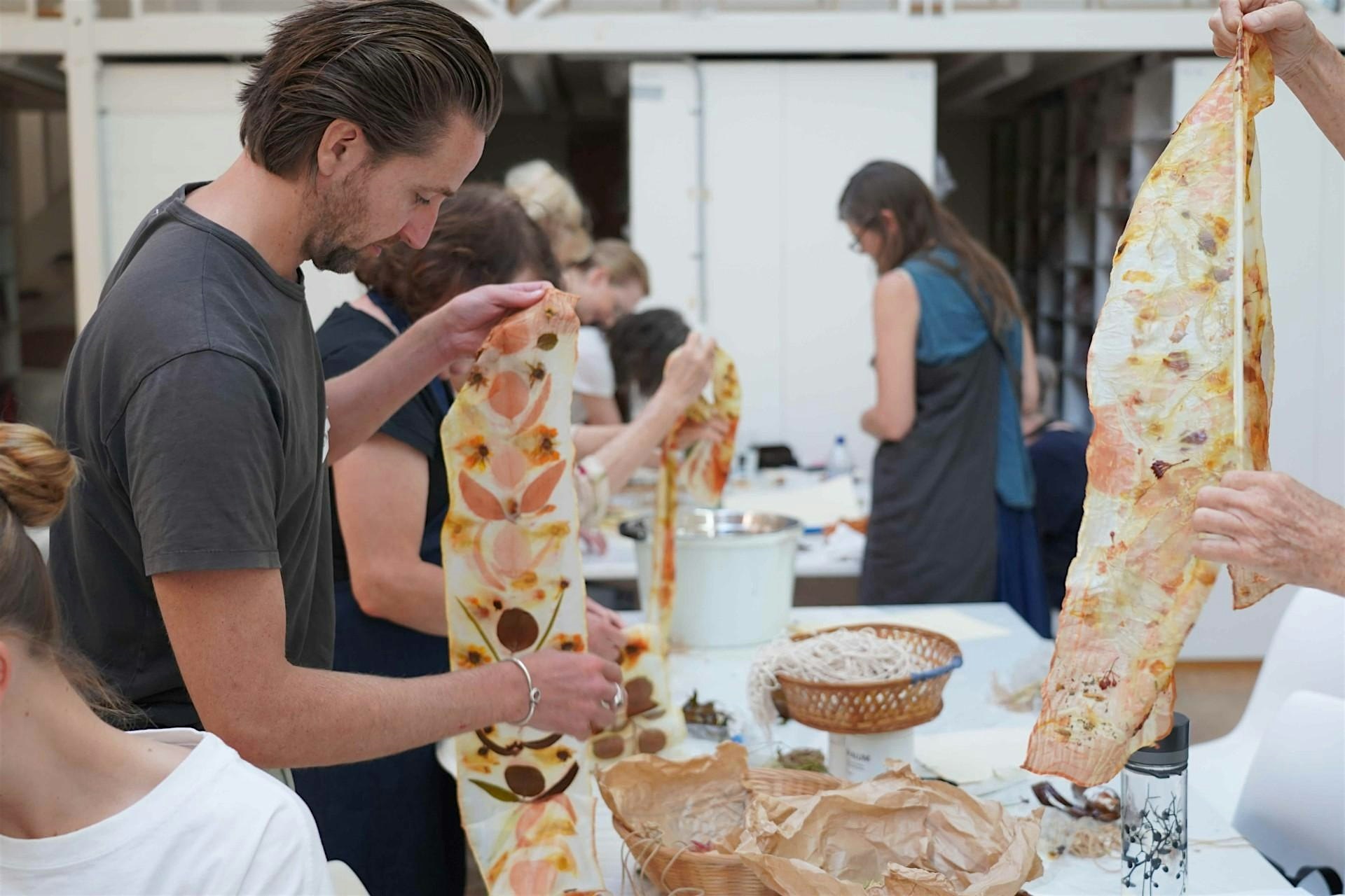 A person works on an eco print project created with colourful flowers