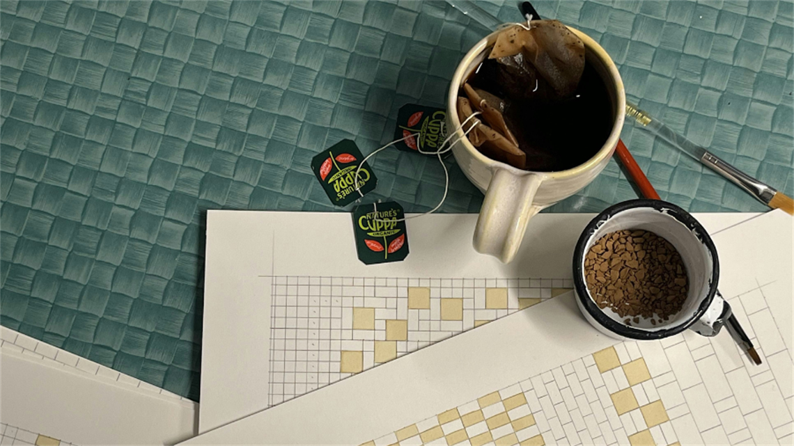 A table with a cup of coffee and a cup of tea with several tea bags