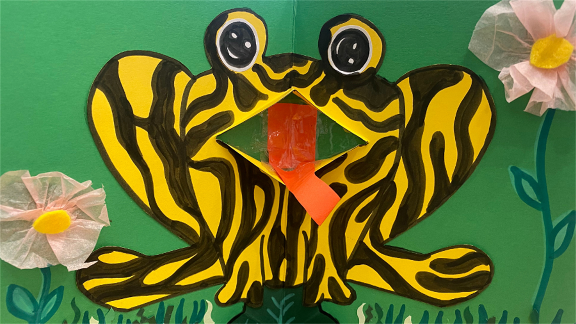 A child's artwork depicting a green papercut frog
