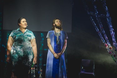 Two people stand next to a plastic bottle streamer.