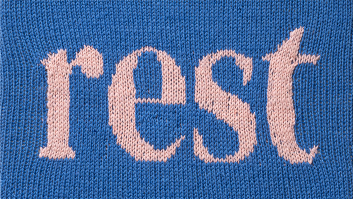 A knitted artwork depicting the word rest